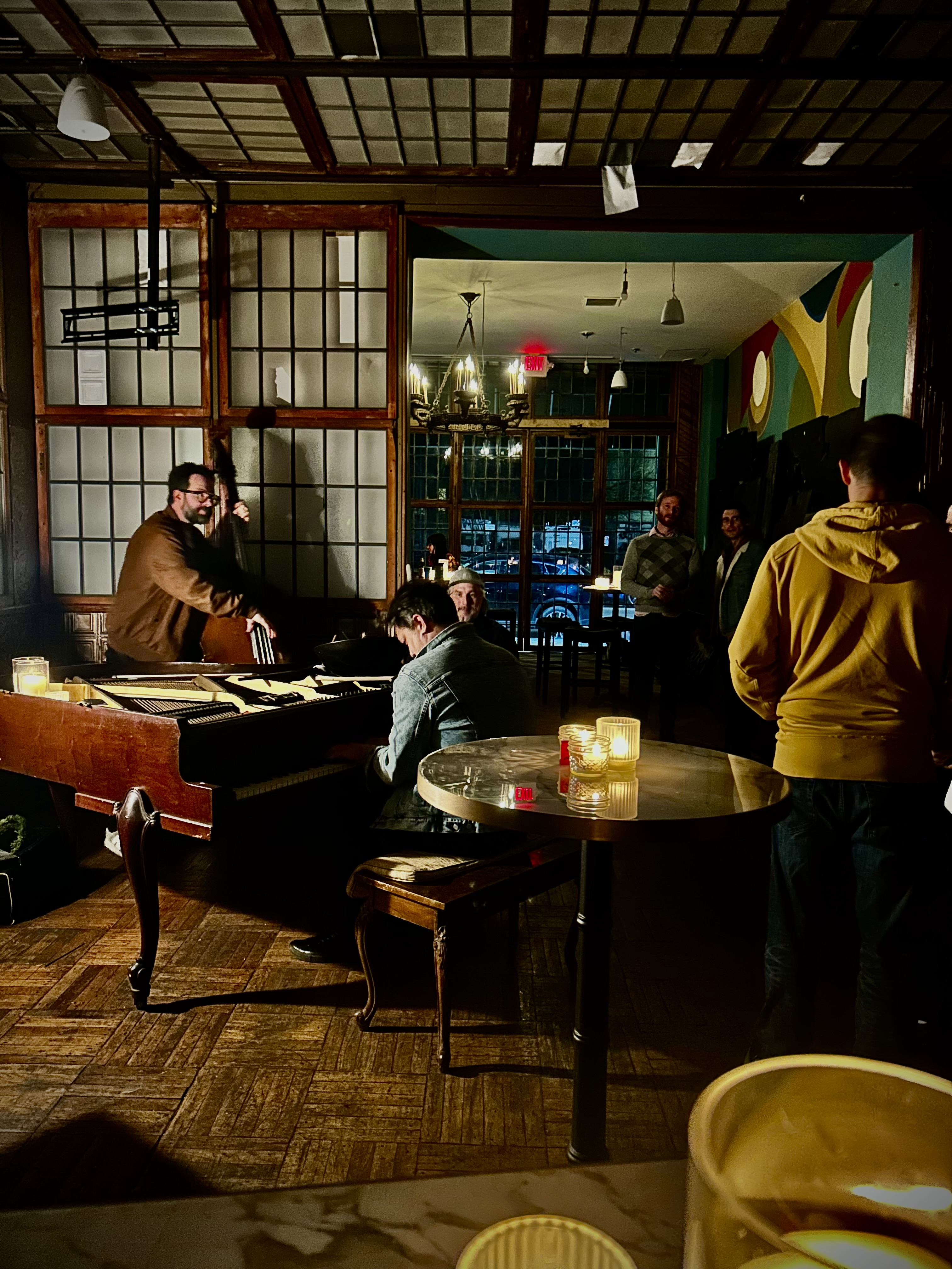 A wide shot of the room with people gathered while the piano is played.